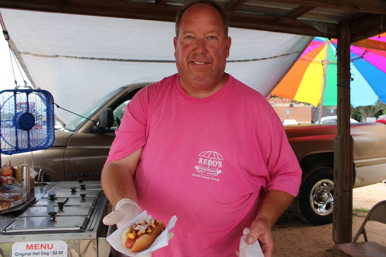 Chris Redd offers a loaded hot dog at his roadside stand in Baldwin County.