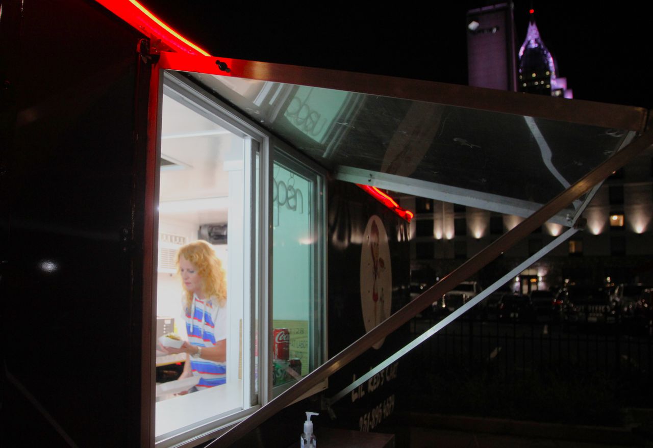 Wendy Clanton prepares a hot dog in her Lil Red's Cart while serving the nutritional needs of the late-night Dauphin Street crowd.