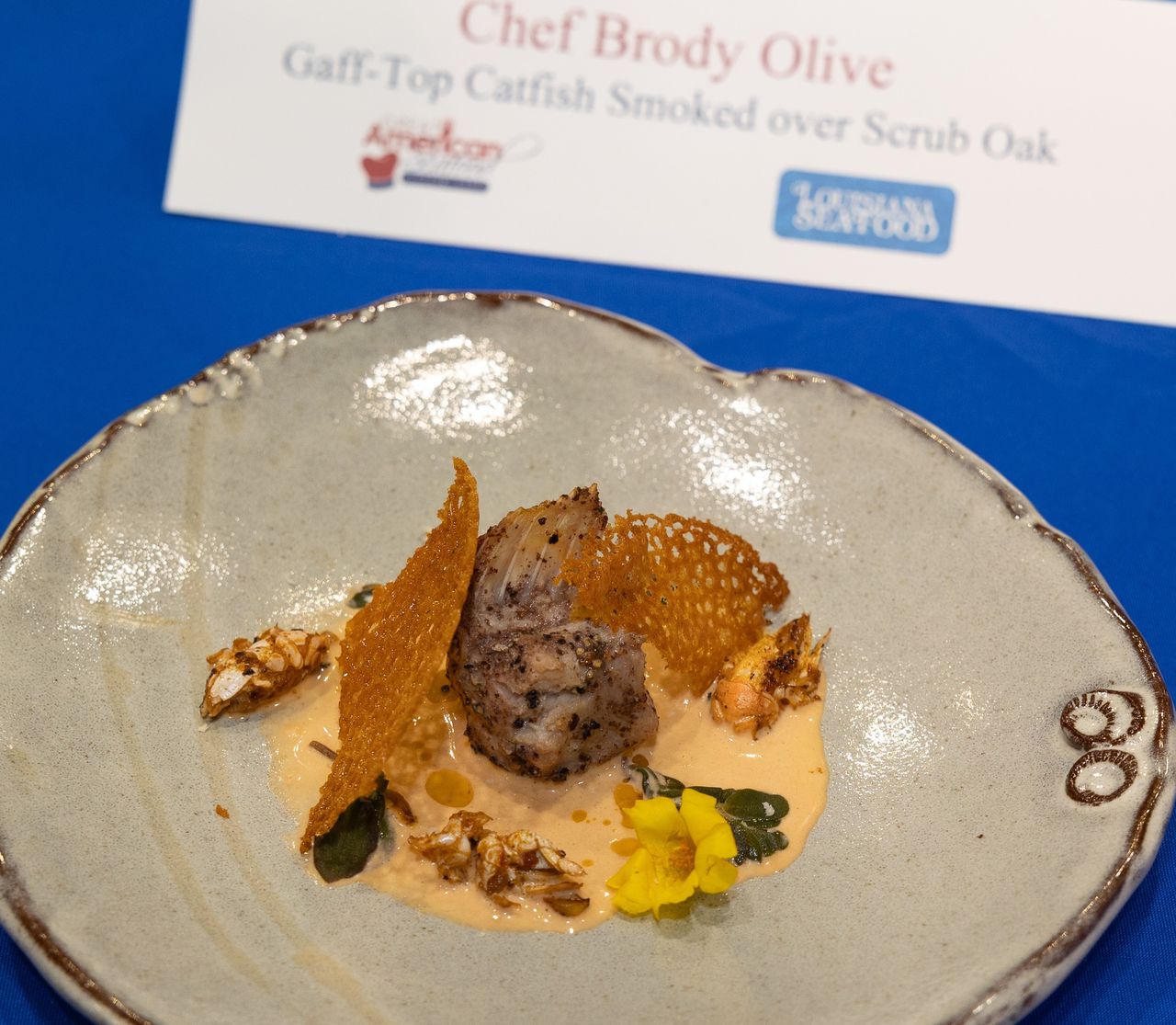 Chef Brody Olive's winning dish at the 2023 Great American Seafood Cook-Off featured gaff-top catfish with flash-fried mole crabs, gulf shrimp horseradish cream, pickled purslane and smoked paprika coral tuile.