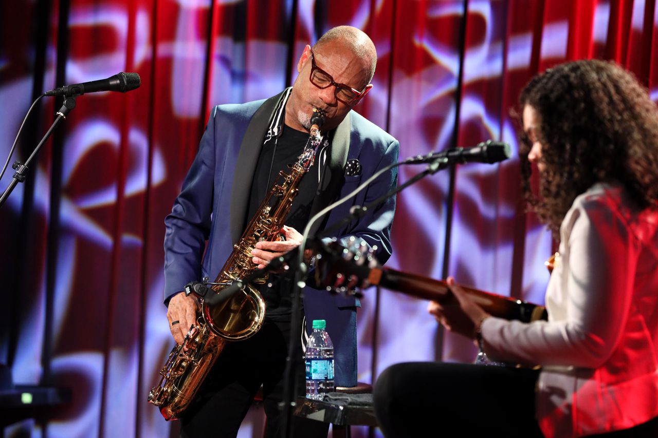 Jazz artist Kirk Whalum leans into the saxophone, accompanied by a guitarist