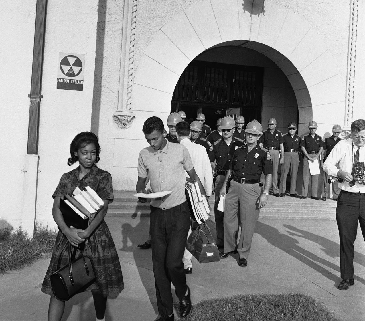 With Alabama State Troopers blocking the main entrance to Murphy High School, students Dorothy Bridget Davis, 16, and Henry Hobdy, 17, arms loaded with school books, turn away from school, Sept. 9, 1963 in Mobile, Alabama. Hobdy is reading his copy of an executive order from Gov. George Wallace stopping the pair from attending classes. Murphy High is Alabama?s largest high school with 3,300 students. (AP Photo/Fred Noel)