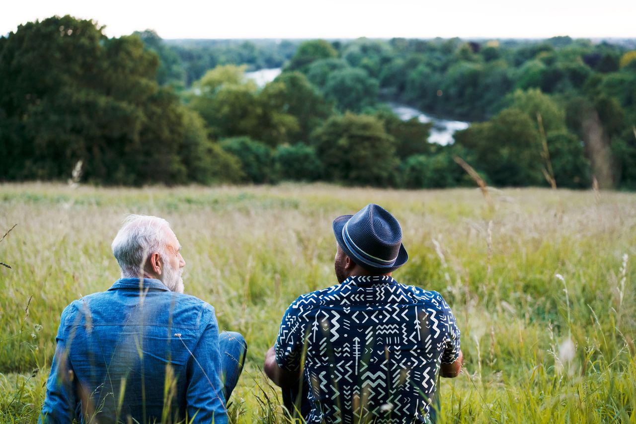 Two men sat, talking, looking at view