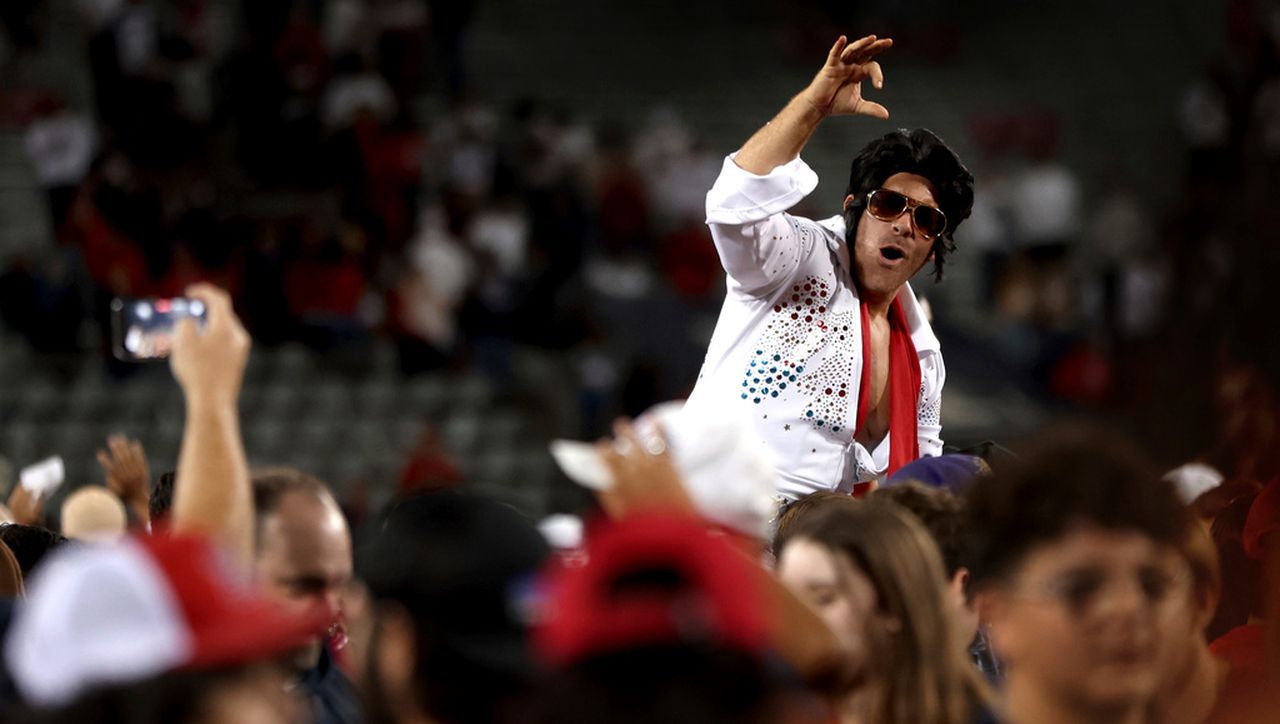 A fan in costume as Elvis crowd surfs as the fans rush the field at Arizona Stadium following the Arizona Wildcats upset of Oregon State of an NCAA college football game Saturday, Oct. 28, 2023, in Tucson, Ariz. (Kelly Presnell/Arizona Daily Star via AP)